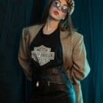 Trendy young woman posing in vintage attire and sunglasses indoors.