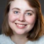 A cheerful woman with short blonde hair smiling indoors, showcasing natural beauty.