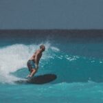 A man skillfully surfing on the vibrant waves of Hawaii under a clear blue sky.